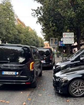 Crni automobili parkirani u nizu duž kaldrmisane ulice