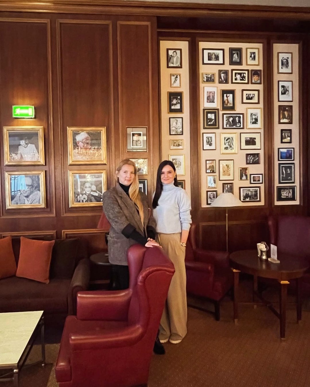 Marija and Maja, the founders, standing side by side in a wood-panelled lounge hung with framed photographs