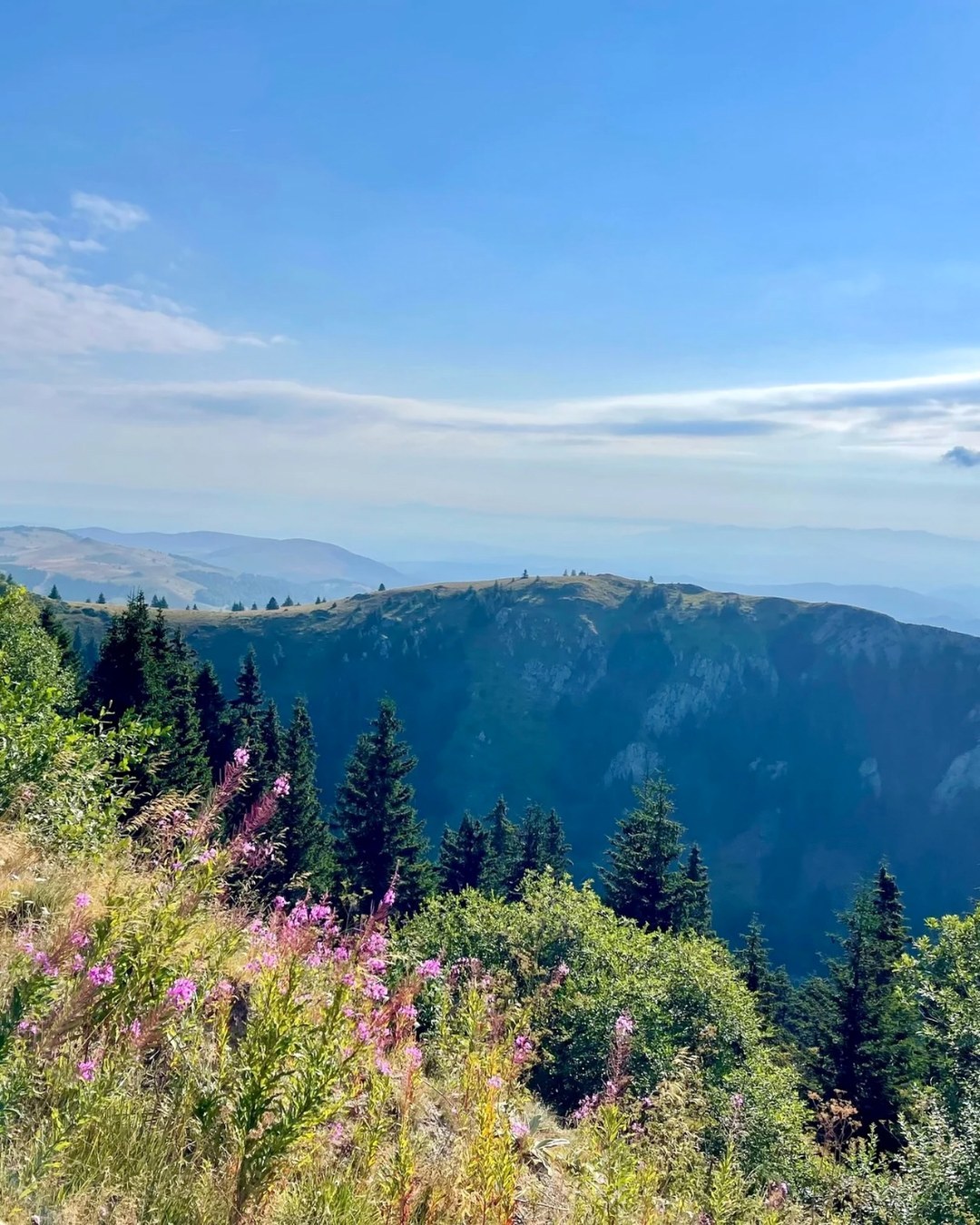Zeleni planinski grebeni pod širokim plavim nebom